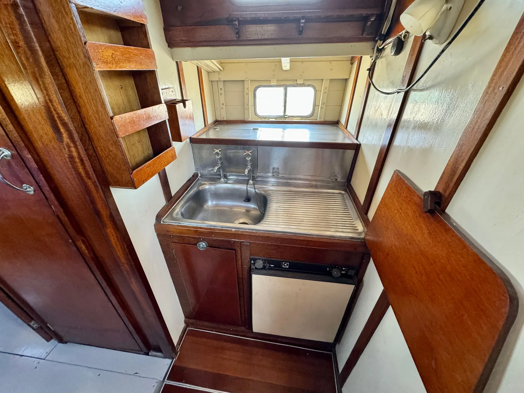 1966 Rampart 48 boat kitchen with wooden cabinetry and stainless steel sink.