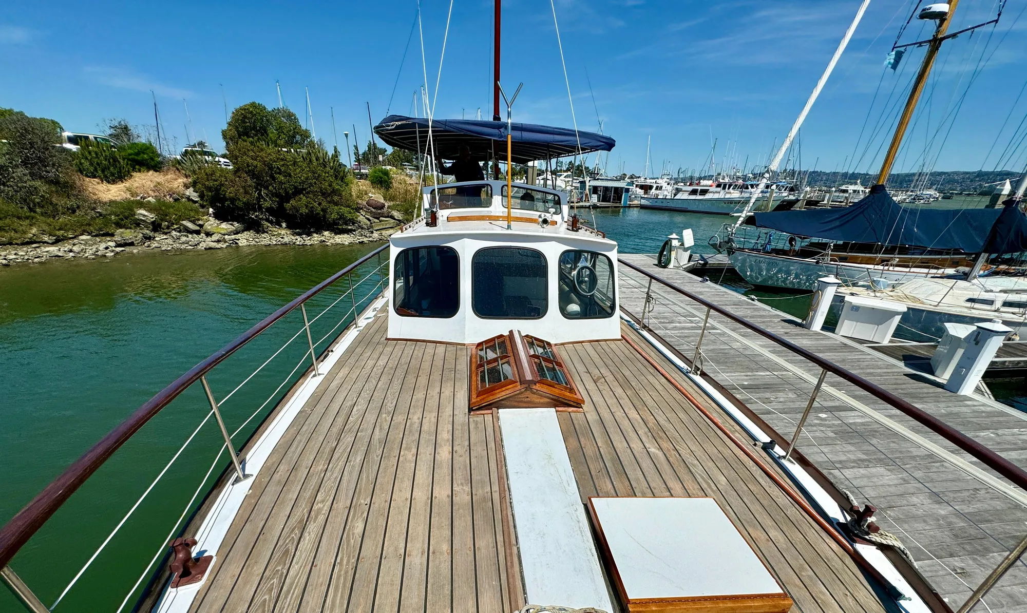 1966 Rampart 48 yacht docked at marina, featuring wooden deck and classic design.
