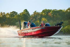 2026 Tracker Savage 215 boat speeding on a lake with two passengers.