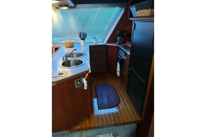  Yacht Photos Pics 1991 Bayliner 4588 Pilothouse kitchen with dual sinks, stove, and wooden cabinetry.