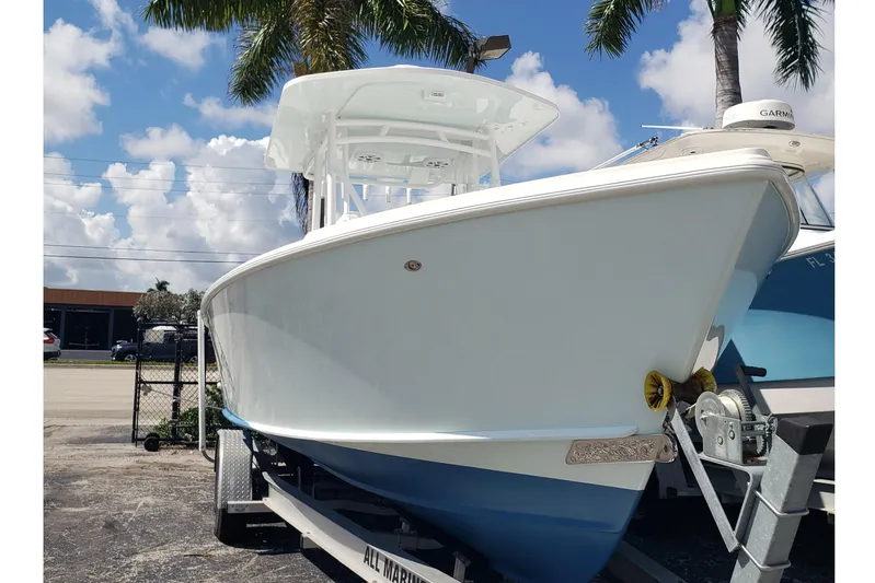 27 Albury Brothers Yacht Photos Pics 2022 Albury Brothers 27 boat on trailer, under palm trees, clear sky background.