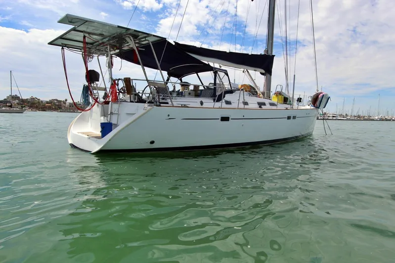  Yacht Photos Pics Sailing yacht Beneteau 473, 2003 model, anchored in calm waters under a partly cloudy sky.