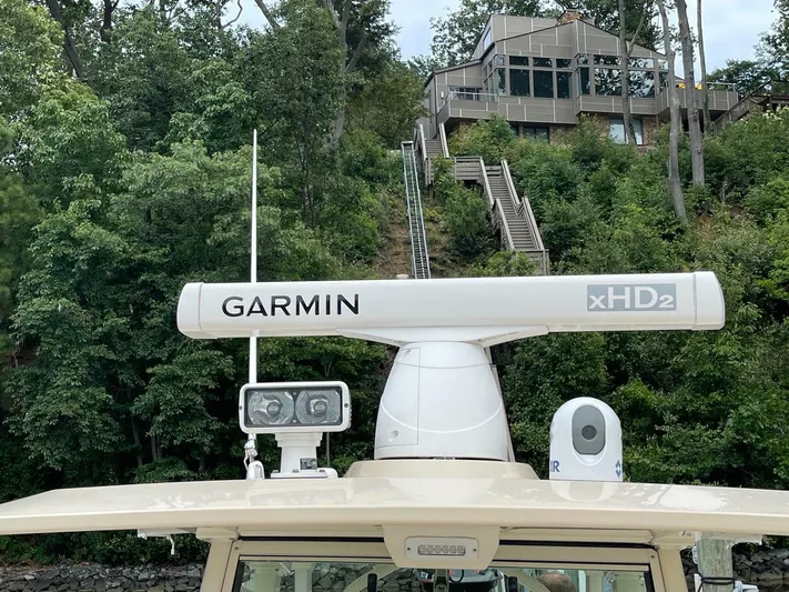  Yacht Photos Pics 2016 Scout 350 LXF boat with Garmin xHD2 radar, surrounded by lush greenery and a modern house.