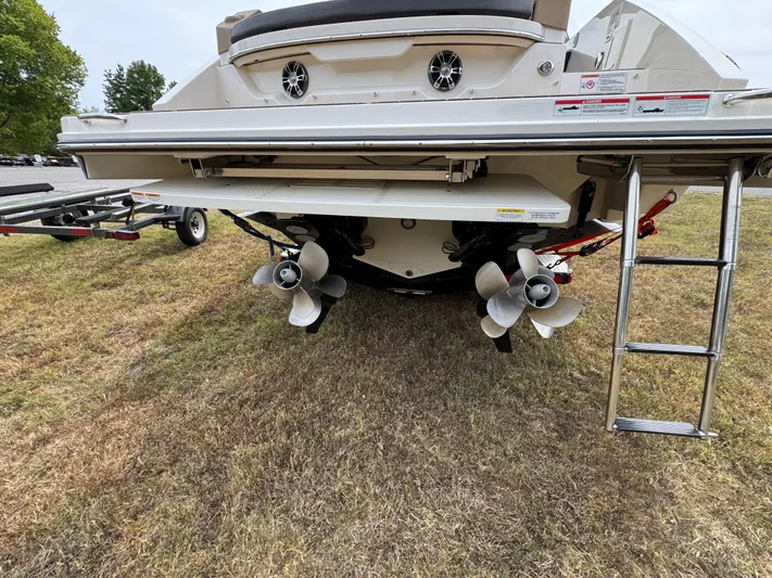  Yacht Photos Pics 2022 Sea Ray SLX 310 boat rear view with dual propellers and ladder on grass.