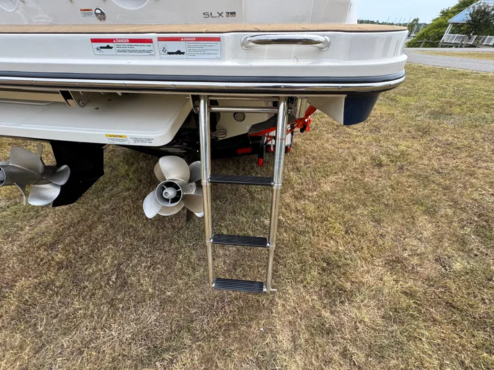  Yacht Photos Pics 2022 Sea Ray SLX 310 boat with ladder and propellers on grassy area.