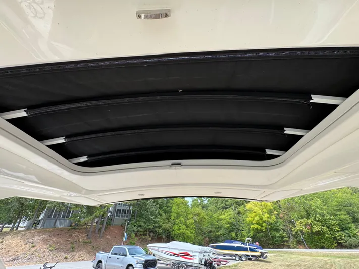  Yacht Photos Pics 2022 Sea Ray SLX 310 boat with retractable sunroof, parked near trees and vehicles.