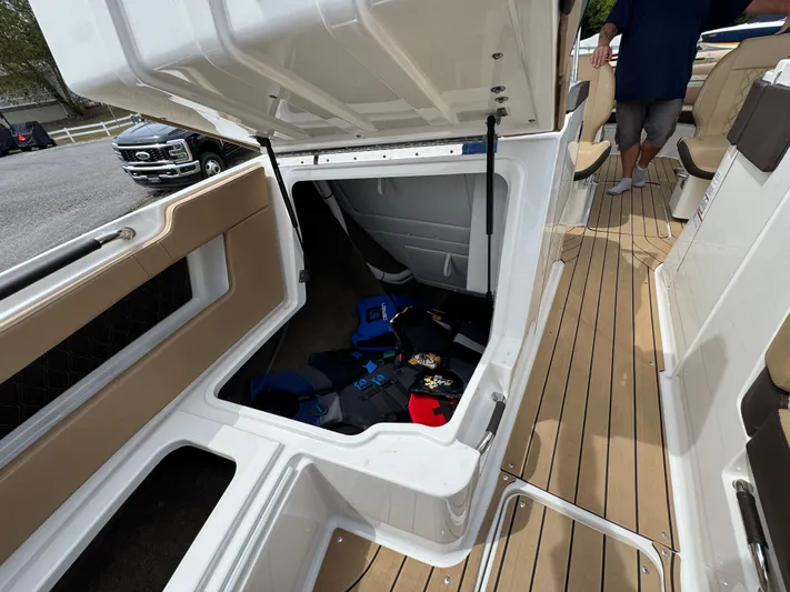  Yacht Photos Pics 2022 Sea Ray SLX 310 boat storage compartment with life jackets, open hatch, and teak flooring.