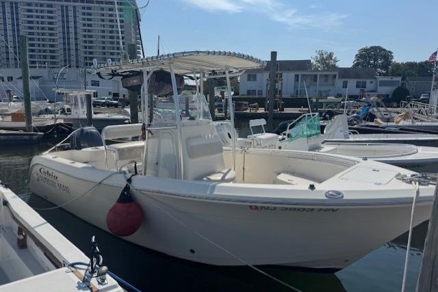 2014 Cobia 217 Center Console boat docked at marina with urban backdrop.