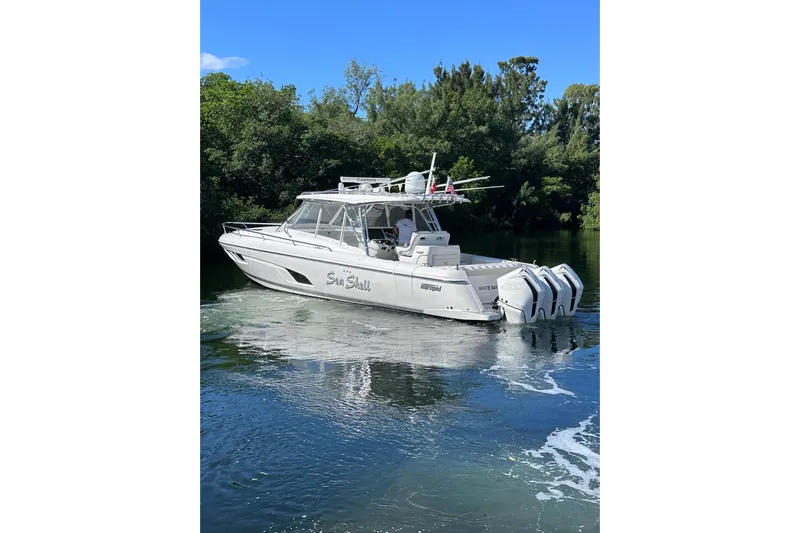 No Name Yacht Photos Pics 2020 Intrepid 409 Valor boat on calm water, surrounded by lush greenery.