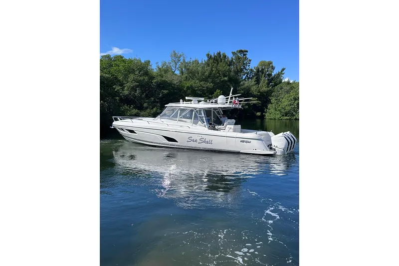No Name Yacht Photos Pics 2020 Intrepid 409 Valor boat on calm water, surrounded by lush greenery.