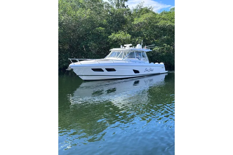 No Name Yacht Photos Pics 2020 Intrepid 409 Valor boat on calm water, surrounded by lush greenery.