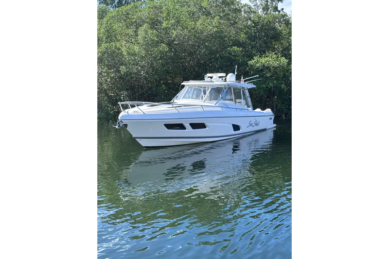 No Name Yacht Photos Pics 2020 Intrepid 409 Valor boat on calm water, surrounded by lush greenery.