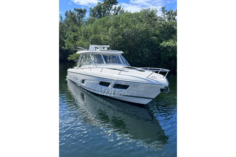 No Name Yacht Photos Pics 2020 Intrepid 409 Valor boat on calm water, surrounded by lush greenery.
