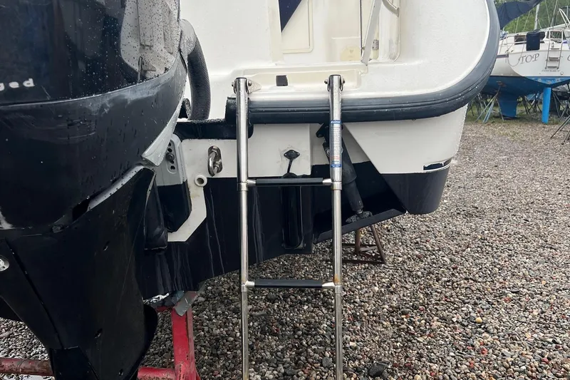 Rock N Reel Yacht Photos Pics 2005 Boston Whaler 305 Conquest boat with ladder on gravel surface.