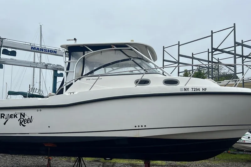 Rock N Reel Yacht Photos Pics 2005 Boston Whaler 305 Conquest boat on land, named "Rock N Reel," with visible registration.
