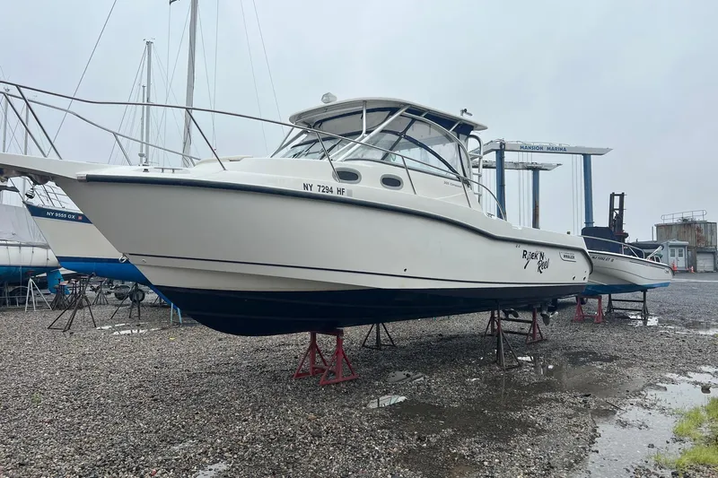 Rock N Reel Yacht Photos Pics 2005 Boston Whaler 305 Conquest boat on stands at marina, overcast day.