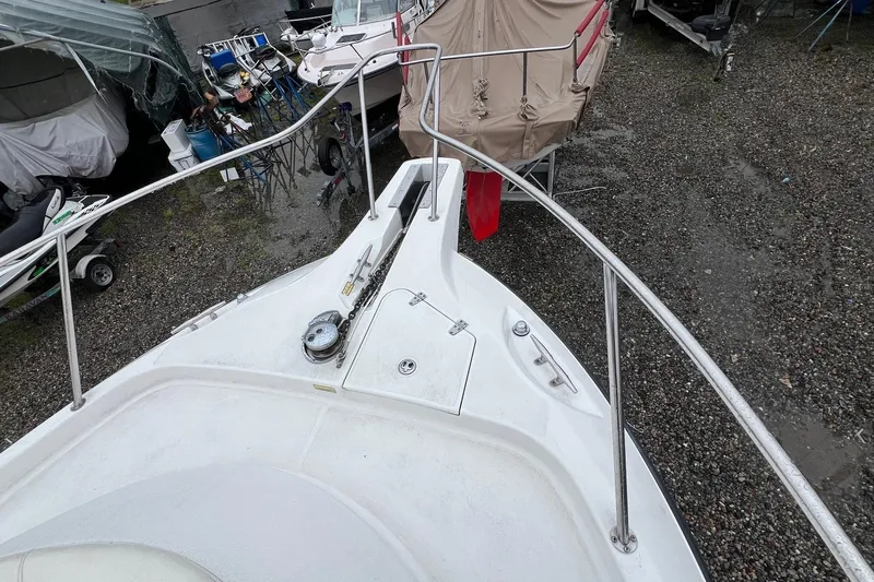 Rock N Reel Yacht Photos Pics 2005 Boston Whaler 305 Conquest boat deck with railing, parked on gravel.