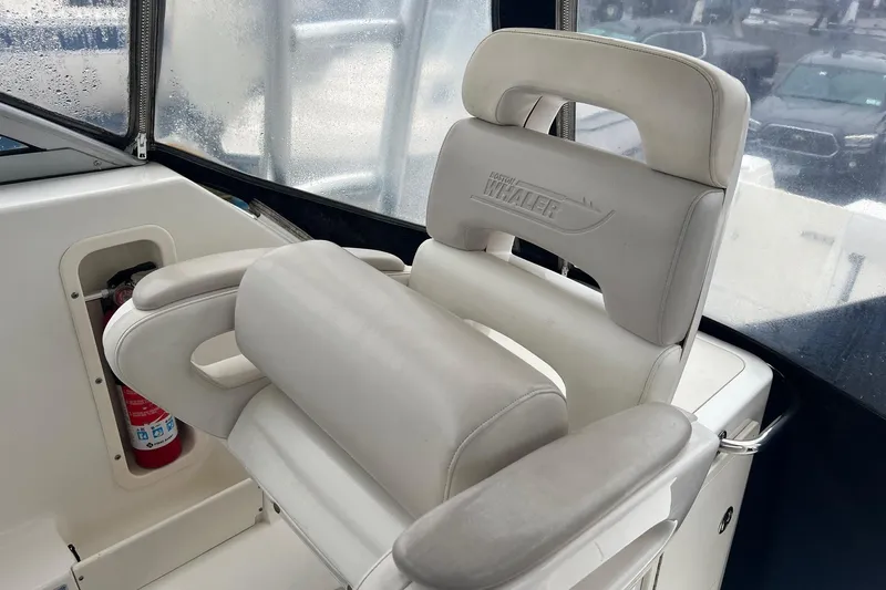 Rock N Reel Yacht Photos Pics 2005 Boston Whaler 305 Conquest helm seat with logo, featuring white cushioned design.