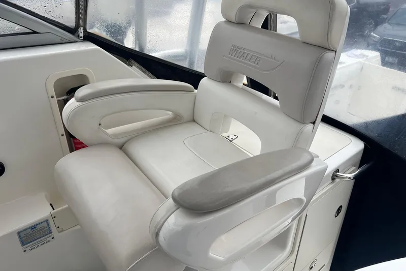 Rock N Reel Yacht Photos Pics White captain's chair on 2005 Boston Whaler 305 Conquest boat, featuring armrests and logo.
