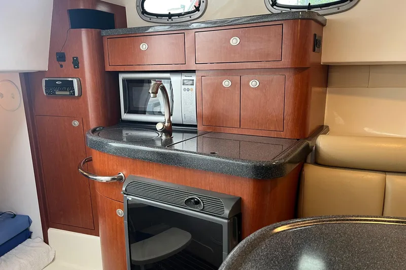 Rock N Reel Yacht Photos Pics 2005 Boston Whaler 305 Conquest interior kitchen with microwave, sink, and wooden cabinetry.