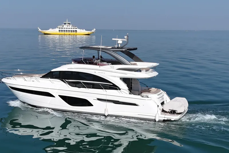  Yacht Photos Pics Luxurious 2019 Princess F62 yacht cruising on calm blue waters with a ferry in the background.