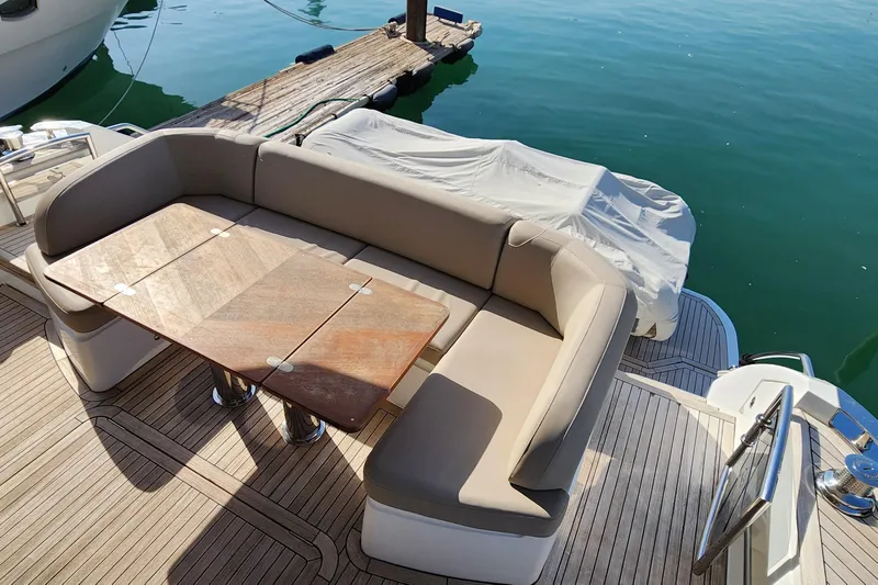  Yacht Photos Pics Luxurious seating area on 2019 Princess F62 yacht with wooden table and dock view.