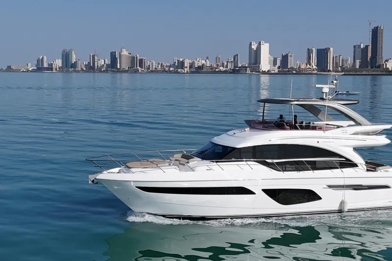  Yacht Photos Pics Luxurious 2019 Princess F62 yacht cruising near a city skyline on calm waters.