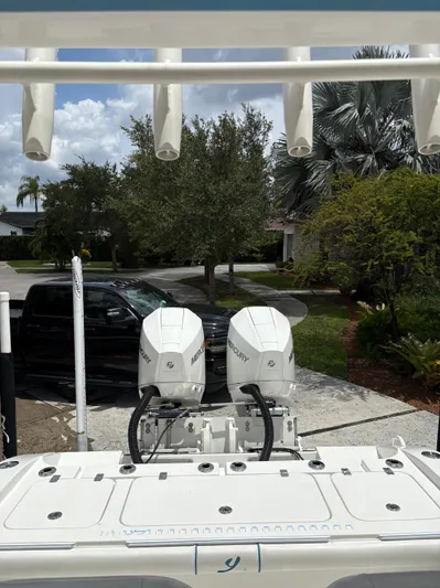  Yacht Photos Pics Boat with dual Mercury engines parked in driveway, surrounded by trees and a black truck.