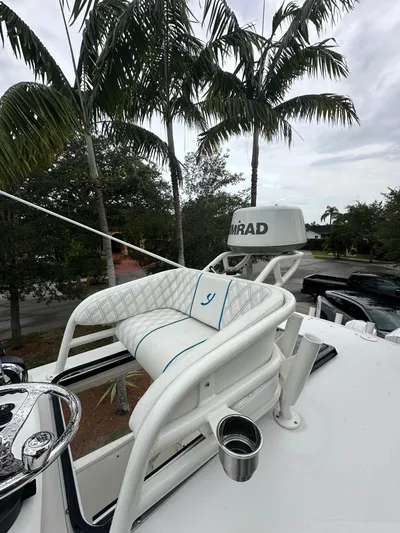  Yacht Photos Pics White boat helm with cushioned seat, palm trees in background, overcast sky.