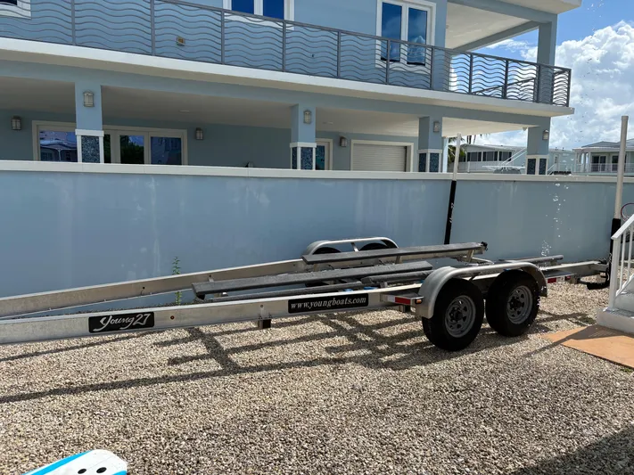  Yacht Photos Pics Boat trailer "Young 27" parked on gravel near a modern blue house, 2019 model.