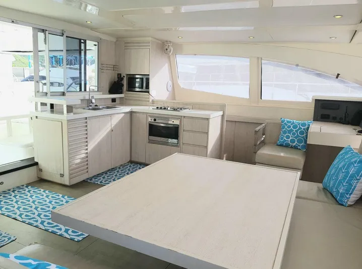 Dash Away Yacht Photos Pics Modern kitchen and dining area inside a 2015 Leopard 51 Powercat yacht, featuring sleek design and blue accents.