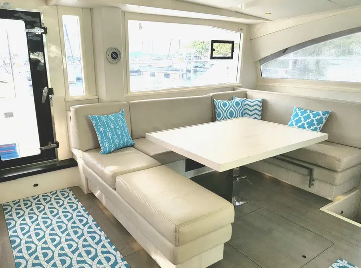 Dash Away Yacht Photos Pics Interior of 2015 Leopard 51 Powercat with beige seating and blue patterned cushions.