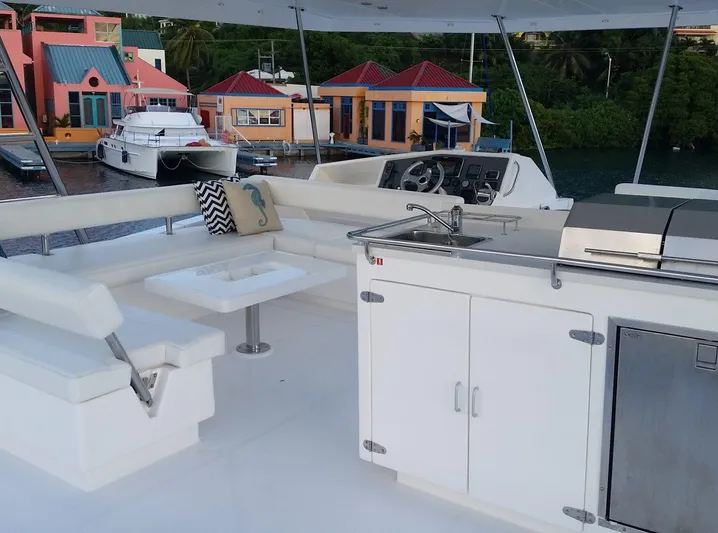 Dash Away Yacht Photos Pics Flybridge of 2015 Leopard 51 Powercat with seating, table, and kitchenette, docked near colorful buildings.