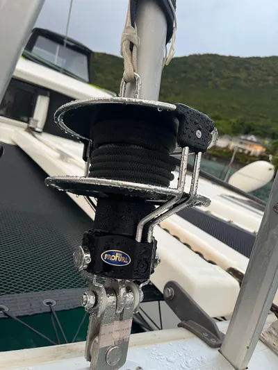Myrto Yacht Photos Pics Close-up of a 2012 Lagoon 400 sailboat rigging component with lush green hills in the background.