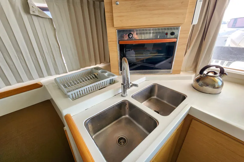 Myrto Yacht Photos Pics Compact kitchen area in a 2012 Lagoon 400 yacht with sink, oven, and kettle.