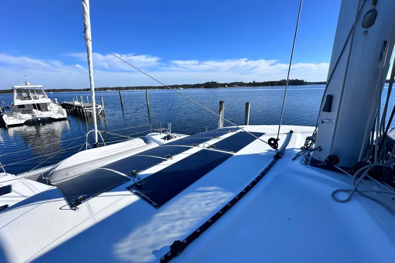 Buena Vida Yacht Photos Pics 2023 Lagoon 50 catamaran docked on serene water under clear blue sky.