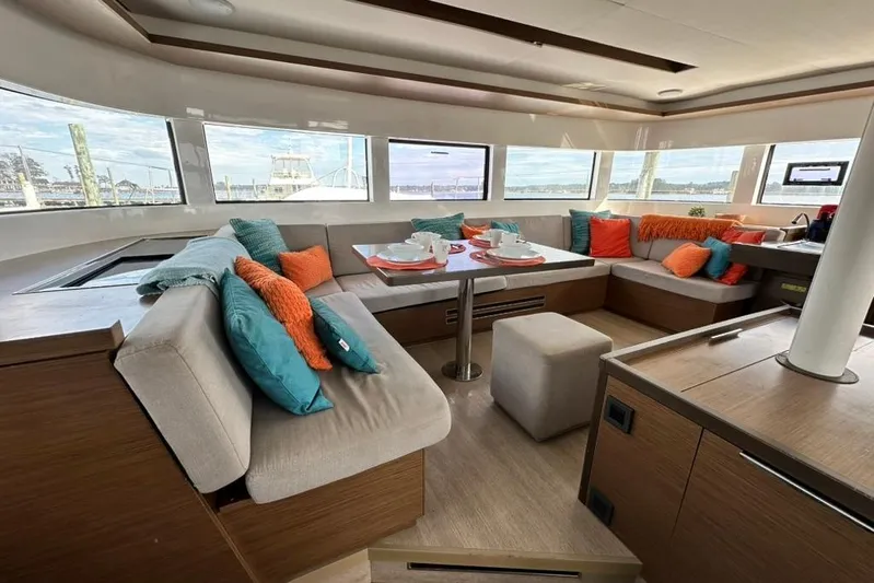 Buena Vida Yacht Photos Pics Luxurious interior of 2023 Lagoon 50 catamaran with colorful cushions and panoramic windows.