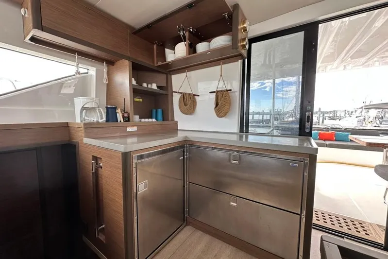 Buena Vida Yacht Photos Pics Modern kitchen interior of 2023 Lagoon 50 yacht with stainless steel appliances and wooden cabinetry.