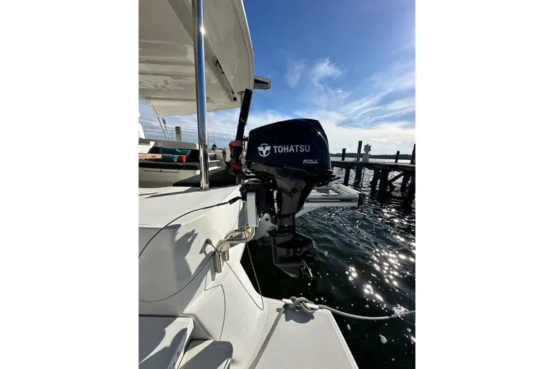 Buena Vida Yacht Photos Pics 2023 Lagoon 50 catamaran with Tohatsu outboard motor, docked by the water.