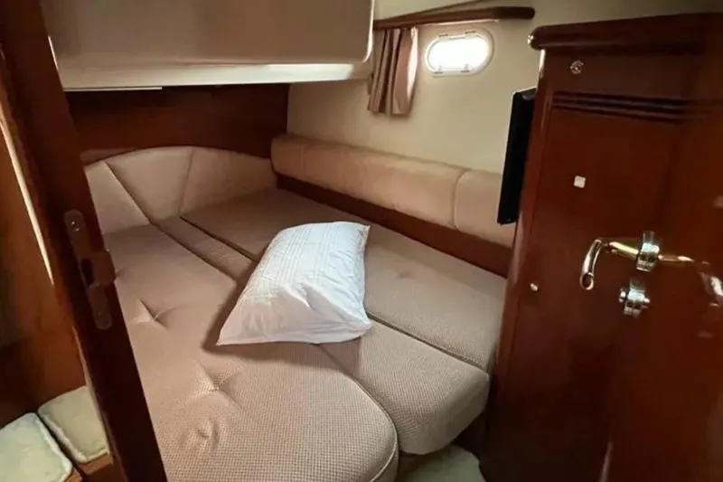 Yacht Photos Pics Cozy cabin interior of 2005 Jeanneau Prestige 46 yacht with bed and porthole.