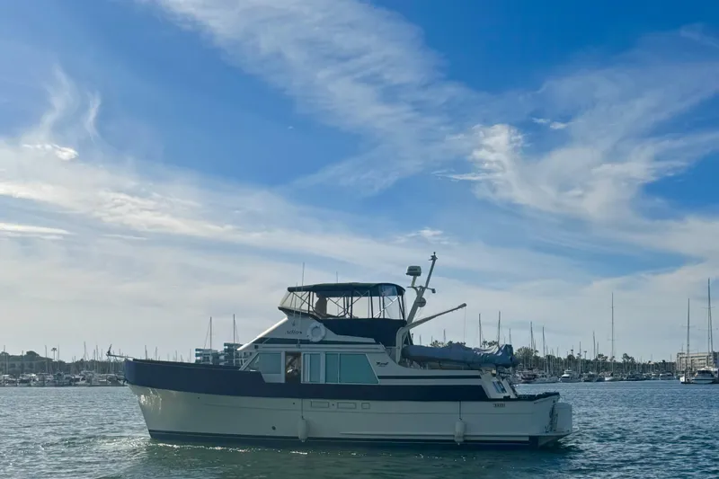 Adios Yacht Photos Pics 1985 Tollycraft 48 Cockpit Motor Yacht on calm water under a clear blue sky.