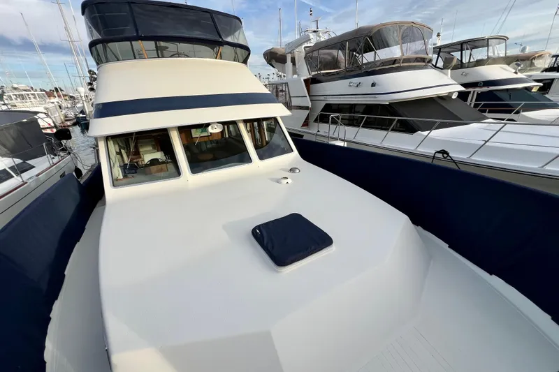 Adios Yacht Photos Pics 1985 Tollycraft 48 Cockpit Motor Yacht docked at marina, surrounded by other boats.
