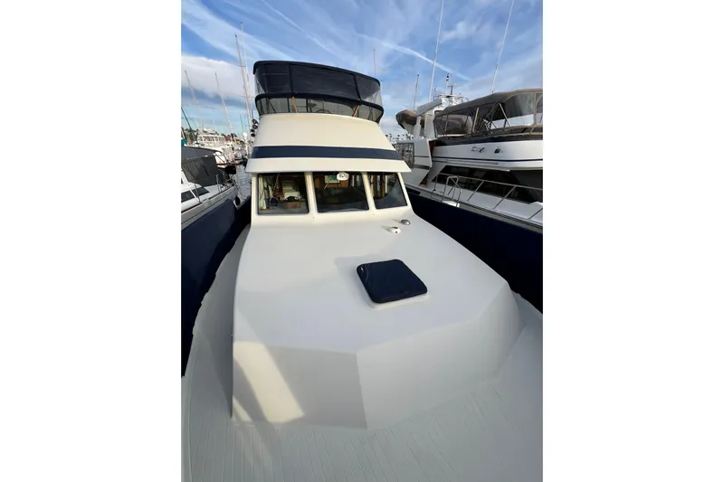 Adios Yacht Photos Pics 1985 Tollycraft 48 Cockpit Motor Yacht docked at marina under blue sky.