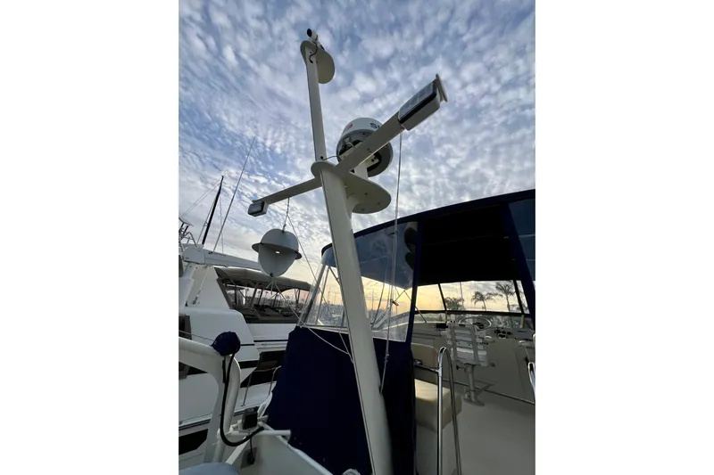 Adios Yacht Photos Pics 1985 Tollycraft 48 Cockpit Motor Yacht with radar equipment against a cloudy sky.