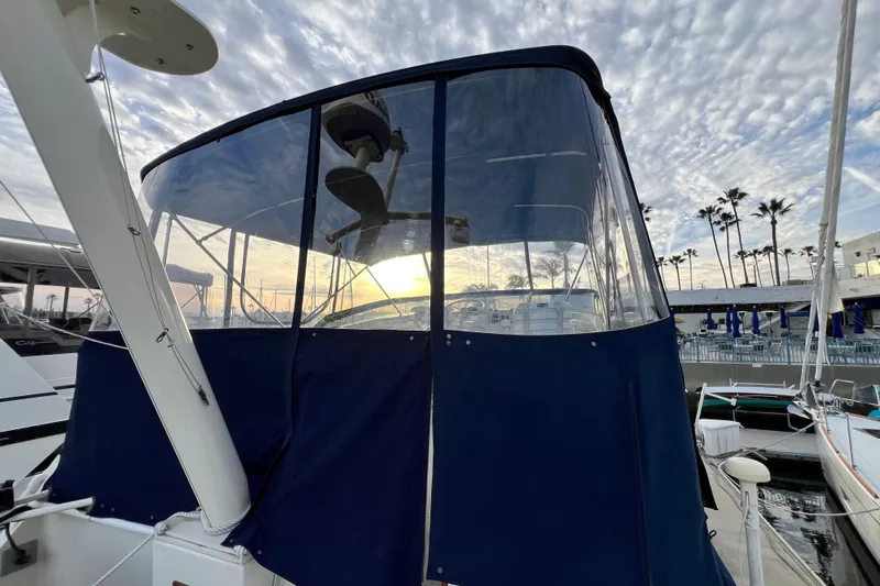 Adios Yacht Photos Pics 1985 Tollycraft 48 Cockpit Motor Yacht at marina, sunset view, blue canopy.