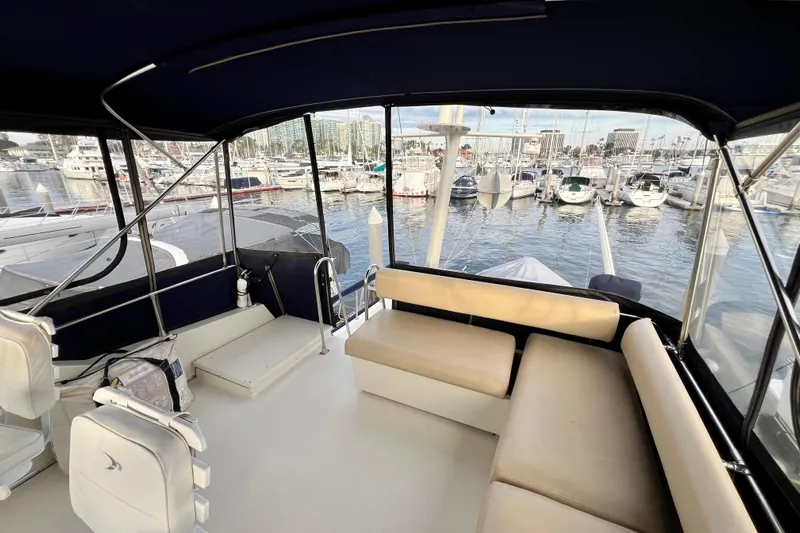 Adios Yacht Photos Pics 1985 Tollycraft 48 Cockpit Motor Yacht interior with marina view, featuring seating and helm area.