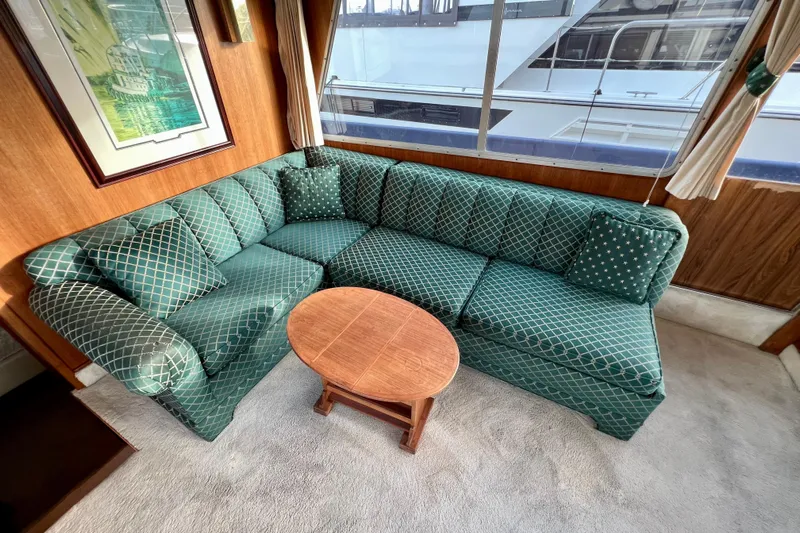 Adios Yacht Photos Pics Interior of 1985 Tollycraft 48 Cockpit Motor Yacht with green patterned sofa and wooden table.