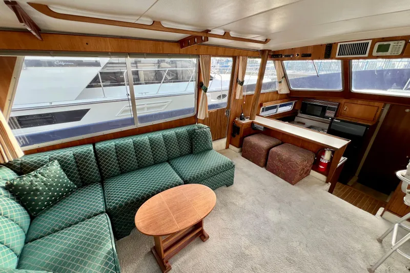 Adios Yacht Photos Pics Interior of 1985 Tollycraft 48 Cockpit Motor Yacht with green sofa and wooden accents.