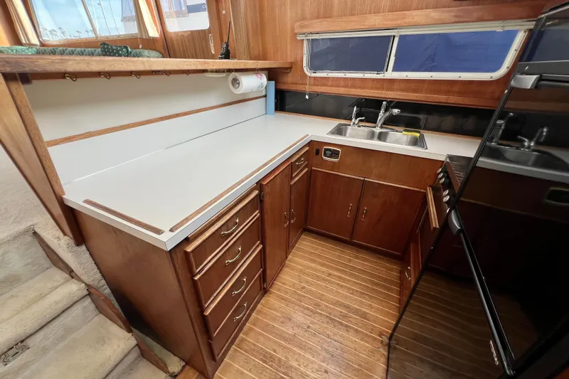 Adios Yacht Photos Pics 1985 Tollycraft 48 Cockpit Motor Yacht kitchen with wooden cabinets and dual sink.