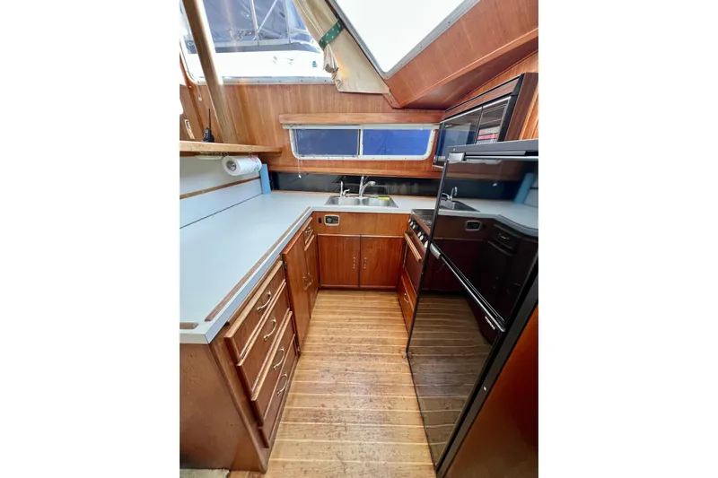 Adios Yacht Photos Pics 1985 Tollycraft 48 Cockpit Motor Yacht kitchen with wood cabinetry and modern appliances.